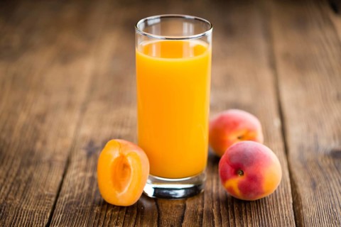 Fresh made Apricot Juice on a vintage background (close-up shot)