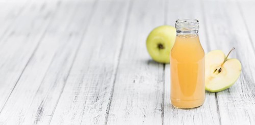 Homemade Apple Juice on an wooden table (selective focus) as detailed close-up shot
