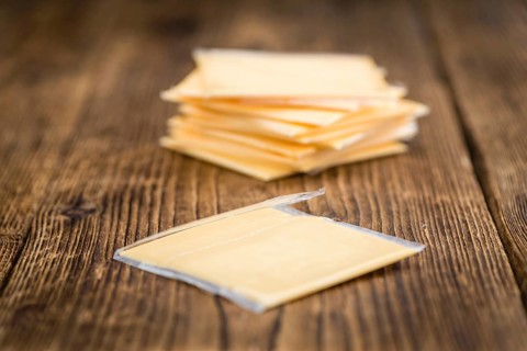 Cheese (sliced) on an old wooden table as detailed close-up shot (selective focus)