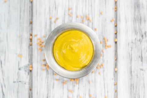Portion of homemade Mustard on wooden background (selective focus, close-up shot)