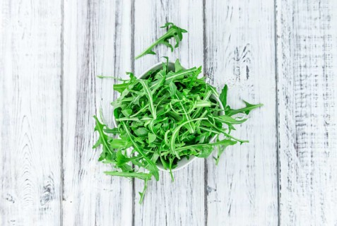 Fresh Arugula on an old wooden table as detailed close-up shot