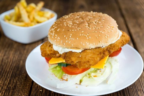Homemade Fish Burger (close-up shot, selective focus) on a wooden table