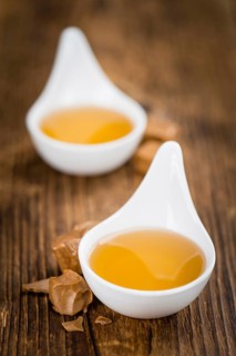 Caramel Syrup as high detailed close-up shot on a vintage wooden table (selective focus)