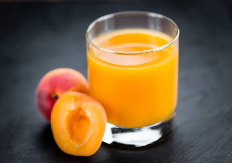 Fresh made Apricot Juice on a vintage background (close-up shot)