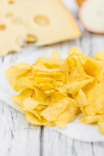 Cheese and Onion Potato Chips on rustic wooden background (close-up shot)