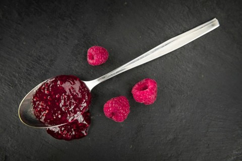 Some Raspberry Jam on a slate slab as detailed close-up shot, selective focus