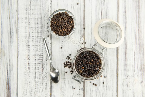 Black Peppercorns preserved on wooden background, selective focus, close-up shot
