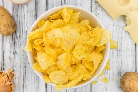 Cheese and Onion Potato Chips on rustic wooden background (close-up shot)