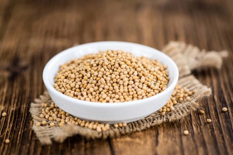 Mustard Seeds on rustic wooden background (close-up shot)