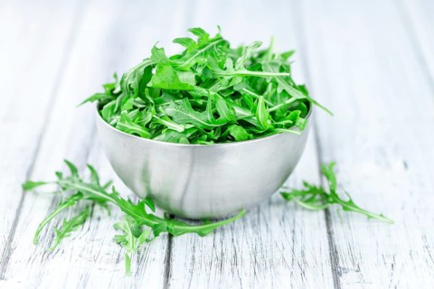 Wooden table with fresh Arugula as detailed close-up shot (selective focus)