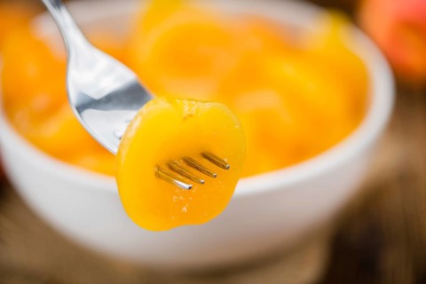 Canned Apricots on an old wooden table as detailed close-up shot (selective focus)