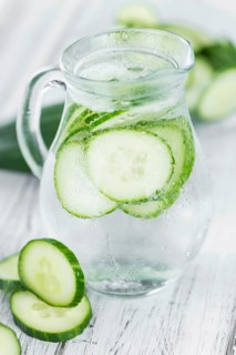 Fresh made Cucumber Water as high detailed close-up shot on a vintage wooden table, selective focus