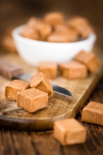 Caramel pieces as high detailed close-up shot on a vintage wooden table (selective focus)