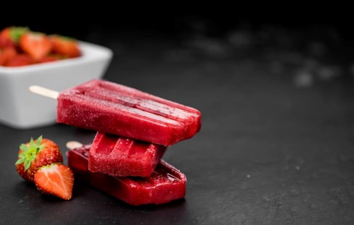 Homemade Strawberry Popsicles (close-up shot, selective focus) on vintage background