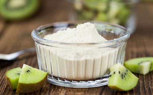 Bowl with fresh made Kiwi powder (close-up shot, selective focus) on an old wooden table