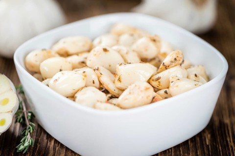 Marinated Garlic on an old wooden table as detailed close-up shot (selective focus)
