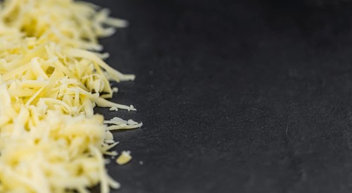 Homemade Grated Cheese (close-up shot) on a vintage slate slab