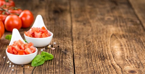 Tomatoes (diced) as high detailed close-up shot on a vintage wooden table (selective focus)