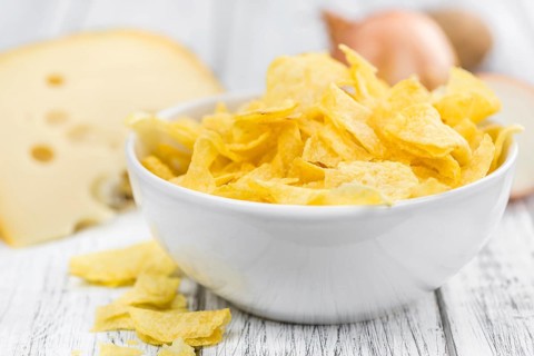 Homemade Cheese and Onion Potato Chips on vintage background (selective focus, close-up shot)
