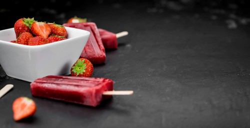 Slate slab with homemade Strawberry Popsicles (selective focus, close-up shot)