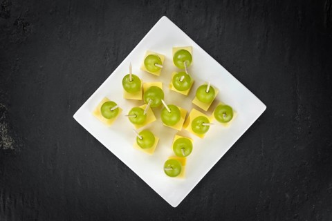 Cheese blocks with grapes as close-up shot on a vintage looking slate slab (selective focus,