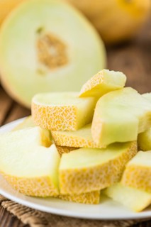 Honeydew Melon on an old wooden table as detailed close-up shot (selective focus)