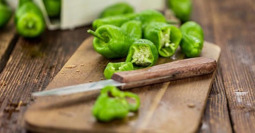 Raw Pimientos on an old wooden table as detailed close-up shot, selective focus