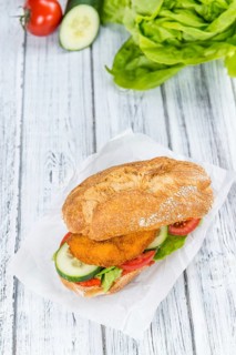 Bun with a Chicken Schnitzel on wooden background (close-up shot, selective focus)