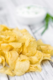 Fresh made Potato Chips with Sour Cream taste on a vintage background (close-up shot)