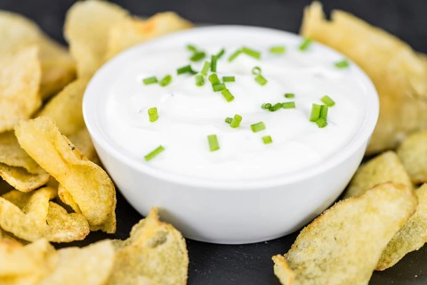 Fresh made Potato Chips with Sour Cream taste on a vintage background (close-up shot)