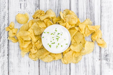 Potato Chips (Sour Cream taste) on a vintage background as detailed close-up shot (selective focus)