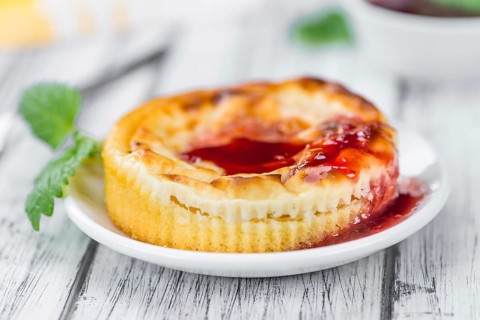 Mini Cheesecake (with Sauce) as high detailed close-up shot on a vintage wooden table (selective