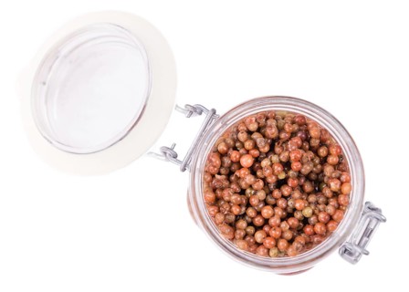 Portion of preserved Pink Peppercorns as detailed close-up shot isolated on white background