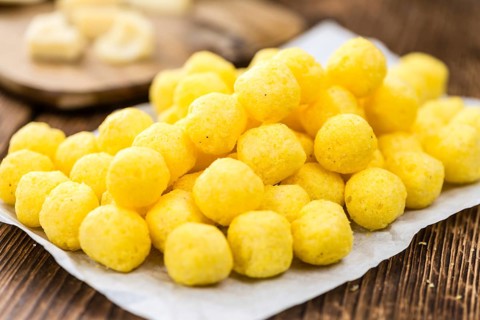 Cheese Balls on an old wooden table as detailed close-up shot (selective focus)