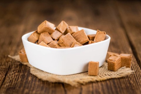 Caramel pieces as high detailed close-up shot on a vintage wooden table (selective focus)