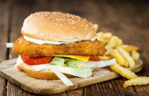 Homemade Fish Burger (close-up shot, selective focus) on a wooden table