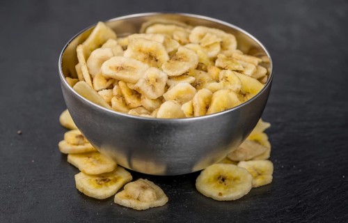 Portion of Dried Banana Chips on a rustic slate slab, selective focus, close-up shot