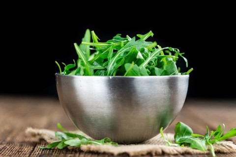 Wooden table with fresh Arugula as detailed close-up shot (selective focus)