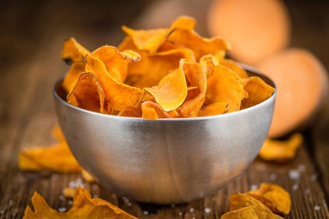 Sweet Potato Chips as high detailed close-up shot on a vintage wooden table, selective focus