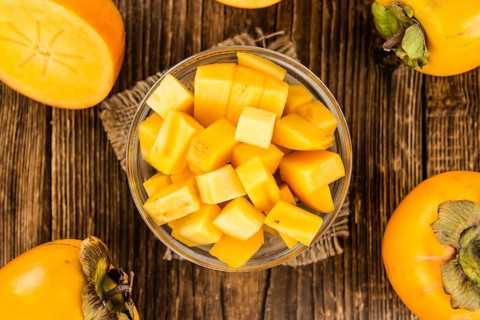 Kaki fruits on rustic wooden background (close-up shot)