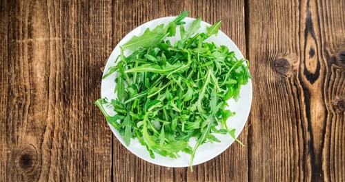 Fresh Arugula (selective focus) as detailed close-up shot on vintage background
