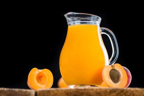 Fresh made Apricot Juice on a vintage background (close-up shot)
