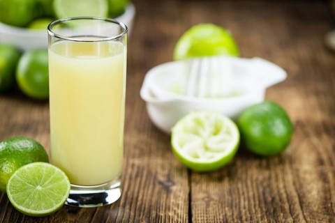 Fresh made Fresh Lime Juice on an old and rustic wooden table (selective focus, close-up shot)