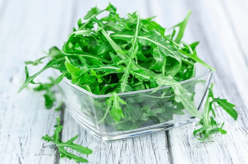 Wooden table with fresh Arugula as detailed close-up shot (selective focus)