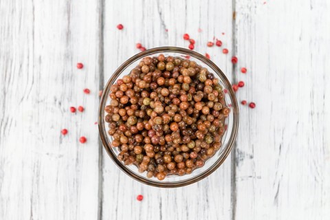 Fresh made Pink Peppercorns (preserved) on an old and rustic wooden table, selective focus,