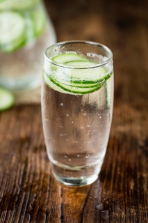 Fresh made Cucumber Water as high detailed close-up shot on a vintage wooden table, selective focus