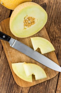 Honeydew Melon on an old wooden table as detailed close-up shot (selective focus)