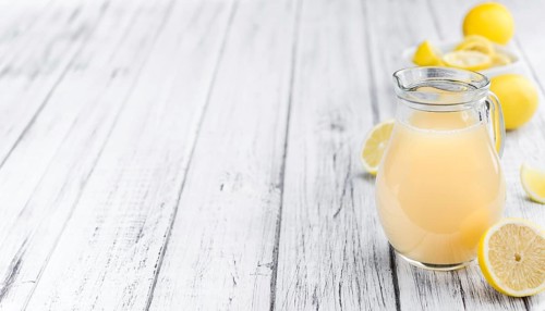 Fresh made Juice (lemon) on an old and rustic wooden table (selective focus, close-up shot)