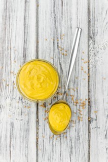 Fresh made Mustard on a vintage background (close-up shot)