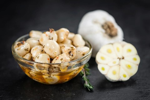 Portion of Garlic (preserved) on a rustic slate slab (selective focus, close-up shot)